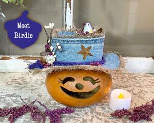 This is a decorative gourd character named Birdie. She is hand-carved with a custom hat made with up-cycled jeans. A candle is included. 